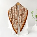 Elegant geometric silk scarf with F-pattern over a white blazer on a wooden hanger - Coffee Geometric Monogram / Brown