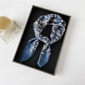 Detailansicht eines dunkelblauen Seidenschals mit weißem Paisley-Muster im Tablett - Blau