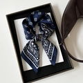 Close-up of a navy blue paisley silk scarf tied in a bow on a white display background - Blue (L7511)