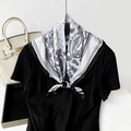 Dettaglio di un foulard in seta bianco e nero con motivo paisley annodato intorno al collo - Base Bianca Con Fiori Neri / Bianco