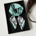 Detail of green paisley silk scarf tied in a decorative knot on a black tray with bag - 70cmx70cm / Cyan