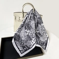 Detail of paisley print silk scarf draped over a leather handbag with sharp contrast - Black and White