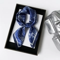 Close-up of navy blue paisley satin scarf tied in a bow inside a premium black gift box - Blue