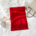 Detail of red cashmere-feel scarf featuring soft fringe tassels on white plush bedding - Red