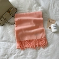 Detail of pink-orange cashmere scarf featuring long fringes on white soft bedding - Bright Pink