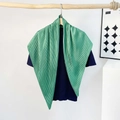 Detail of emerald green pleated silk scarf draped elegantly on a deep blue top - Pleating / Green
