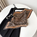 Detail view of a pleated leopard print silk scarf styled with fashion accessories - Orange Border Leopard