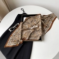 Detail of pleated silk scarf featuring golden paisley pattern on black dress background - Coffee Paisley