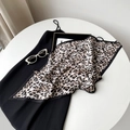 Close-up of leopard print pleated silk scarf paired with a minimalist black strap dress - Black and White Leopard Print