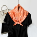 Elegant orange silk neck scarf with white paisley pattern tied over black top - Orange