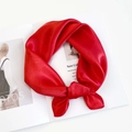 Detailed view of a bright red satin scarf tied in a knot on a fashion magazine - Orange Red
