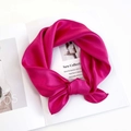 Detail of a magenta silk scarf tied in a bow on a fashion magazine for luxury styling - Magenta