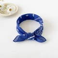 Close-up of knotted dark blue paisley bandana with classic white patterns and daisy decor - 50cm x 50cm / Royal Blue
