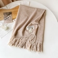 Detail van een licht camel kasjmier sjaal met lange franjes en luxe metalen merklabel - Khaki