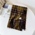 Détail de l'écharpe à carreaux jaunes et marron avec franges sur fond de table blanche - Café Jaune