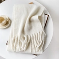 Dettaglio di sciarpa bianca in mohair con frange su un tavolo con accessori - 40x210cm / Bianco