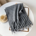 Dettaglio di una sciarpa in maglia grigio scuro con lunghe frange su vassoio in legno - 40x210cm / Grigio scuro