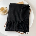 Sciarpa spessa in mohair nero con lunghe frange su un tavolo in un ambiente accogliente - 40x210cm / Nero