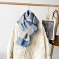 Blau-weiß karierter Strickschal mit dicker Fleece-Textur auf einer weißen Steppjacke - Blau Karo