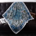 Blue silk square scarf with palm leaf and floral patterns on a leather sofa - Blue Exotic Print
