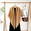 Close-up of camel tassel shawl on a hanger with Financial Times and luxury accessories - Khaki