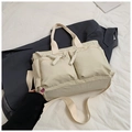 Macro detail of cream nylon tote bag featuring front zipper pockets and woven pullers - Off White