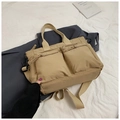 Detail view of khaki nylon tote bag featuring dual front pockets and woven zipper pulls - Khaki