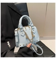 Detailansicht der hellblauen Muscheltasche mit Goldketten und Metallnieten-Verzierung - Blau