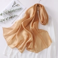 Detail of elegant champagne satin scarf draped over white shirt with glossy silk finish - Caramel color