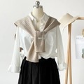 Detail of beige knit shawl texture with woven brand tag over a white shirt - Khaki