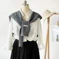 Detailed view of gray knitted shawl wrap with brand tag over a white collared shirt - Gray