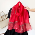 Detail of red silk shawl featuring gold metallic trim and elegant pearl embellishments - Red