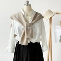 Chal de punto calado beige sobre camisa blanca, ideal para un estilo en capas - Caqui