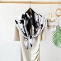 Elegant 90cm black and white floral satin silk scarf draped on a chic dress neckline - Magnolia Black
