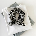 Zijdeachtige vierkante sjaal met zwart-wit luipaardmotief platgelegd op casual kleding - 55x55cm / Luipaard Wit