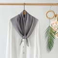 Detail view of a grey pleated chiffon scarf styled on a white shirt with aesthetic props - Gray