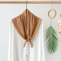 Detail of camel pleated chiffon scarf draped on a wooden hanger with aesthetic props - Yellow