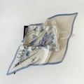 Detail of white pleated silk scarf featuring light blue floral prints and wavy edges - Plissé Pleated / Blue Lotus