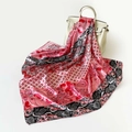 Dettaglio di un foulard in raso con motivo paisley drappeggiato su una borsa - 90x90cm / Rosso