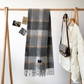 Detail of grey plaid cashmere scarf showing soft fringe and 100% blend woven label - Gray
