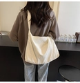Sac hobo minimaliste en velours côtelé beige porté par un mannequin pour le quotidien - Blanc