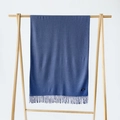 Blue cashmere shawl with fringe detail hanging on a minimalist wooden display stand - Denim Blue