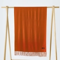 Rust red cashmere scarf with fringe details on a wooden hanger with white background - Orange Red