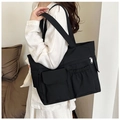 Detailed side view of black canvas tote bag showing utility pockets and sturdy shoulder straps - Black