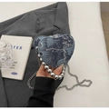 Close-up of heart-shaped blue denim handbag with silver bead handle and metal chain - Blue