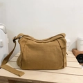 Minimalist khaki canvas messenger bag with adjustable shoulder strap on wooden table - Tan