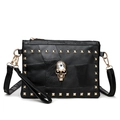 Close-up of black leather crossbody bag with golden skull and square rivets detail - Black