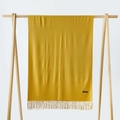 Close-up of ginger yellow cashmere shawl with fringe details on a wooden stand - Turmeric / 215*70cm