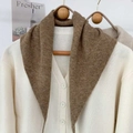 Dettaglio del cardigan in maglia crema con sciarpa triangolare marrone su gruccia - Caffè