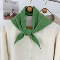 Dettaglio di una sciarpa a triangolo in maglia verde su un cardigan crema con texture - Verde